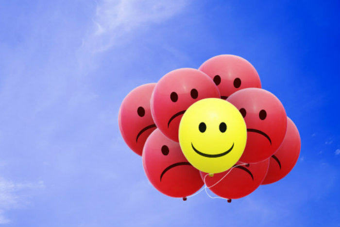 Cluster of balloons with frowning faces and one with a smiley face 