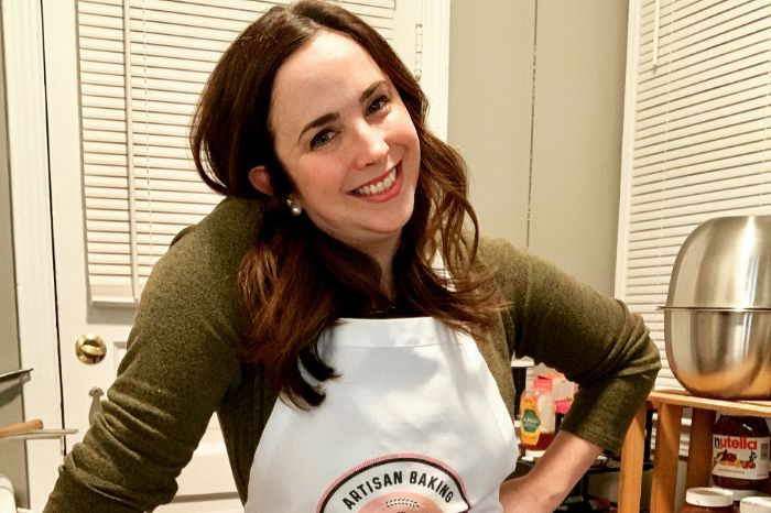 Meghann Hennen poses in a kitchen wearing an apron
