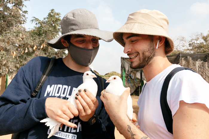Two men holding doves in their hands while wearing bucket hats