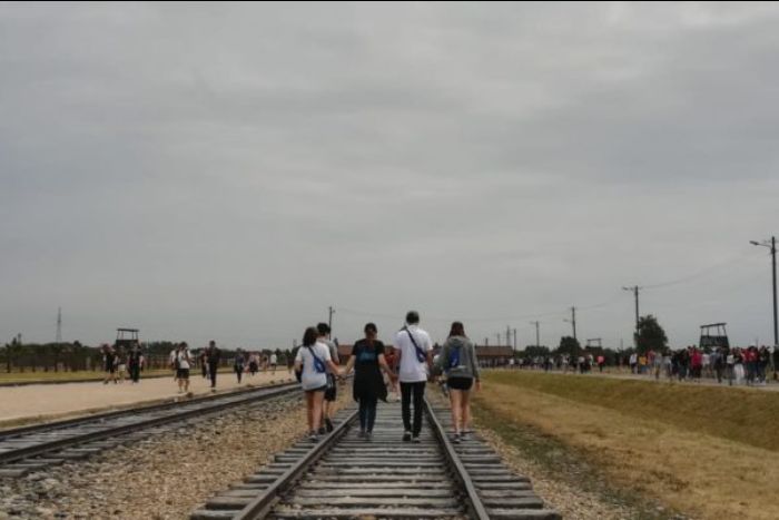 Teenagers walking down railroad tracks while visiting a concentration camp
