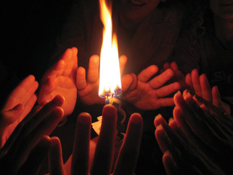 Hands surrounding a candle used in the Jewish holiday of Havdallah at the end of Shabbat