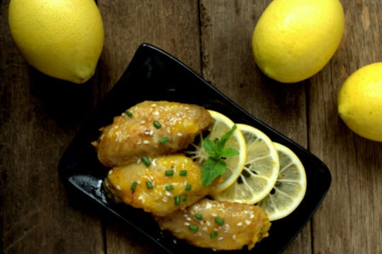 Chicken on a black plate with lemons