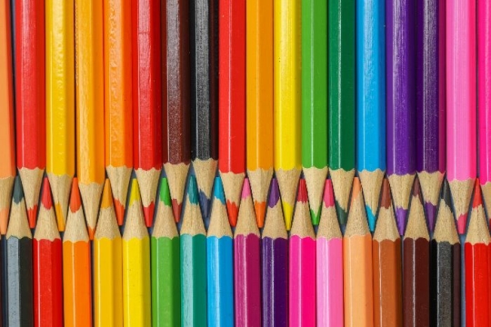 A rainbow of colored pencils pointing downwards and upwards with points touching