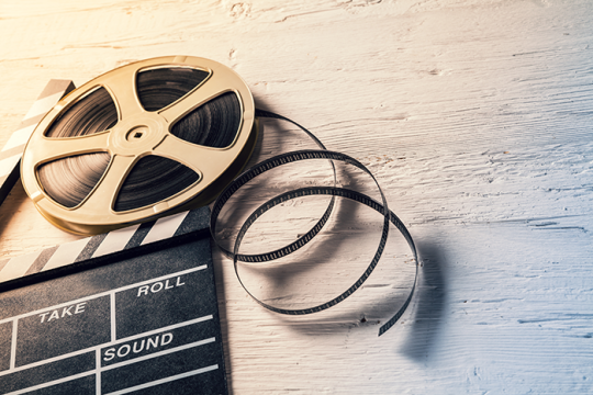 an image of a film reel and film slate laying on a wooden background