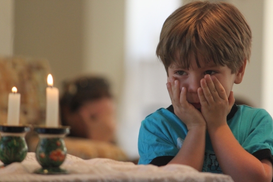 A child praying over candles for the Jewish holiday of Shabbat